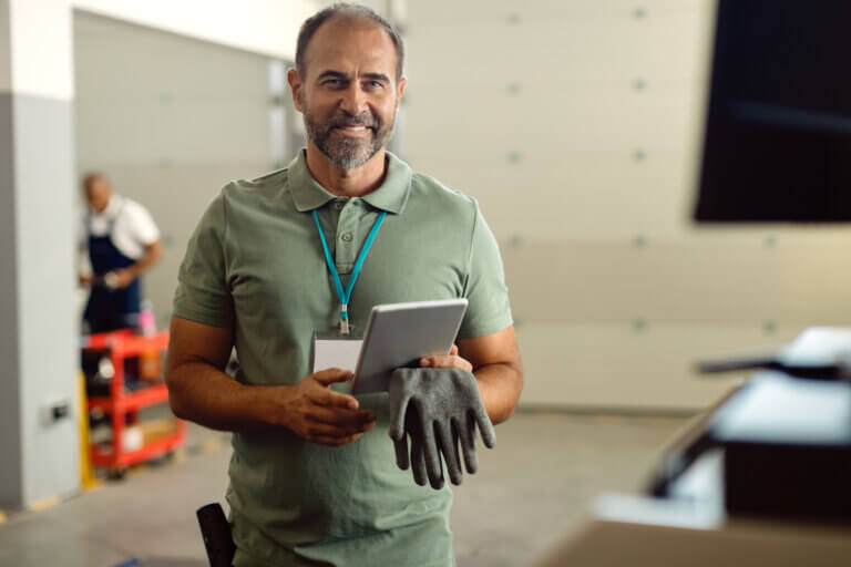 happy foreman auto mechanic workshop using touchpad looking camera